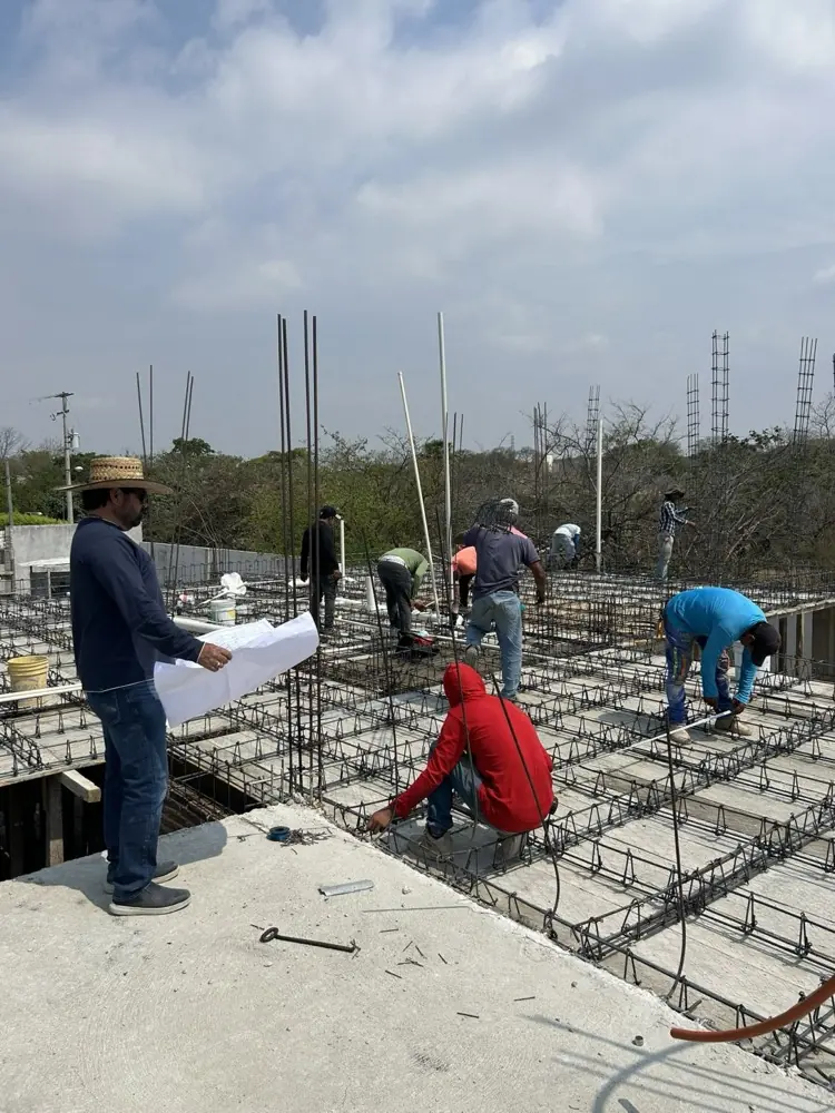 Cuadrilla armando una losa reticular mientras el arquitecto revisa planos